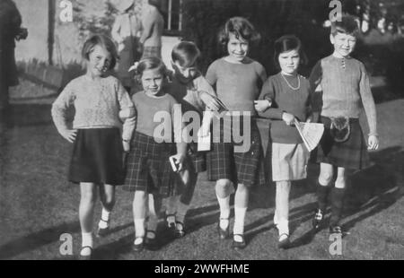 Una fotografia cattura la principessa Elisabetta II, insieme a sua sorella la principessa Margaret, mentre si godeva la festa del sesto compleanno di James Carnegie presso il terreno di Elsick House il 23 settembre 1935. Questa immagine offre uno sguardo sull'infanzia della futura regina e di sua sorella, partecipando a una gioiosa celebrazione con i pari, che riflette i momenti più personali e giocosi della vita reale prima dell'ascesa al trono di Elisabetta. Foto Stock