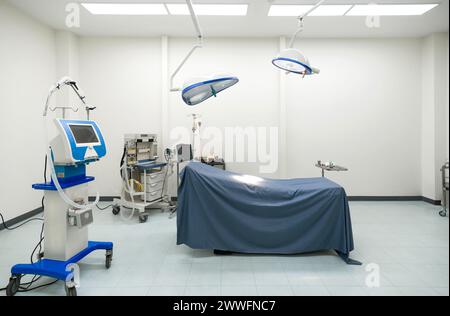Una tipica sala operatoria in un ospedale con una lampada chirurgica sopra la testa per fornire un'illuminazione luminosa e direzionale all'équipe chirurgica durante la procedura. Foto Stock
