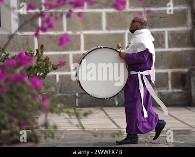 Antigua, Guatemala. 23 marzo 2024. Un penitente porta un tamburo di basso nella Chiesa Escuela de Cristo prima dell'inizio di una processione di Quaresima del Cristo de las Misericordias, 23 marzo 2024 ad Antigua, Guatemala. Le sontuose processioni, le dettagliate alfombre e le tradizioni secolari attraggono oltre 1 milione di persone nell'antica capitale. Crediti: Richard Ellis/Richard Ellis/Alamy Live News Foto Stock