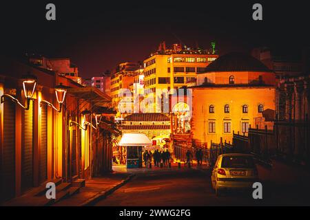 La notte scende sulla città, con l'architettura storica che si illumina sotto le luci della strada. Foto Stock