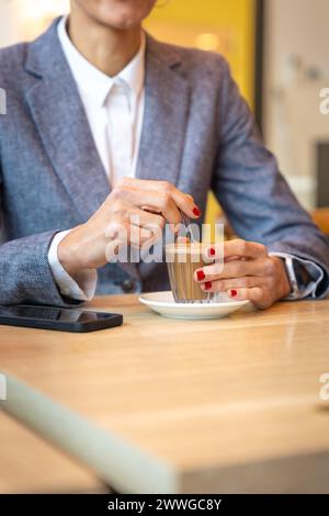Immagine verticale irriconoscibile donna elegante che beve un caffè al bar. Foto Stock