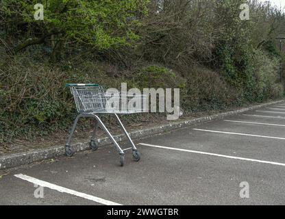 Carrello e cestino del supermercato abbandonati in un parcheggio. Foto Stock