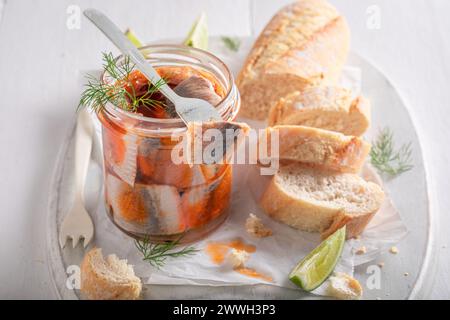 Pesce marinato delizioso e fresco come fonte di buon grasso. Aringhe in vaso servite con pane. Foto Stock