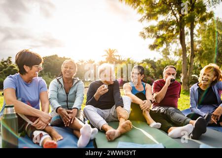 Amici anziani multirazziali felici bevendo un tè dopo le attività di allenamento in un parco Foto Stock