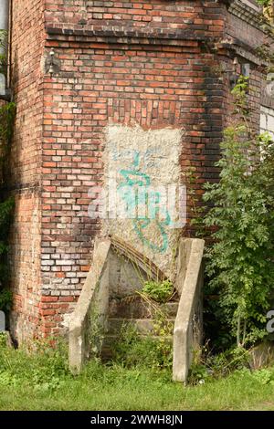 Scala abbandonata e porta abbandonata sigillata con calcestruzzo in un vecchio edificio residenziale in mattoni desolati a Danzica, Polonia, Europa, UE Foto Stock