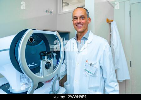 Ritratto di un oftalmologo in una clinica innovativa in piedi accanto a una macchina laser per il trattamento del glaucoma Foto Stock