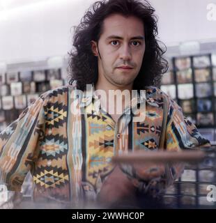 Primo piano di un ragazzo con lunghi capelli neri e una camicia colorata Foto Stock
