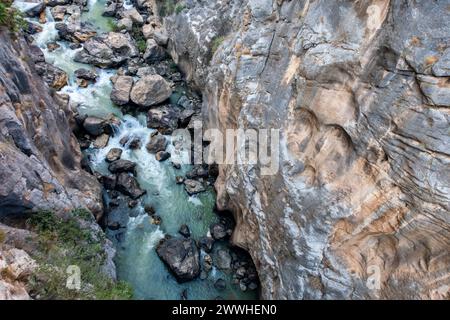 El Caminito del Rey nella gola di El Chorro, Spagna, vista dall'alto del profondo precipizio con fiume selvaggio, rocce e pietre. Foto Stock