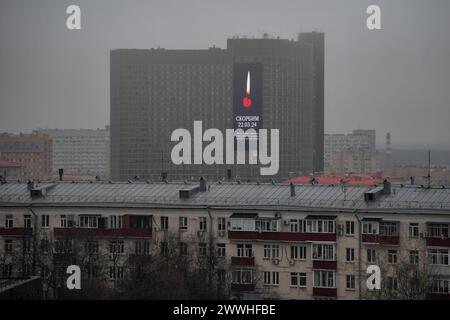 Mosca. 24 marzo 2024. Questa foto scattata il 24 marzo 2024 mostra un cartellone che mostra l'immagine di una candela per piangere le vittime di un attacco terroristico a Mosca, in Russia. Venerdì sera, uomini armati non identificati spararono indiscriminatamente contro i frequentatori di concerti al municipio di Crocus, nella periferia di Mosca, causando gravi perdite civili. In un discorso nazionale trasmesso in televisione sabato, il presidente russo Vladimir Putin ha promesso di identificare e punire tutti coloro che hanno causato l'attacco e ha dichiarato il 24 marzo un giorno di lutto nazionale. Crediti: Alexander Zemlianichenko Jr/Xinhua/Alamy Live News Foto Stock