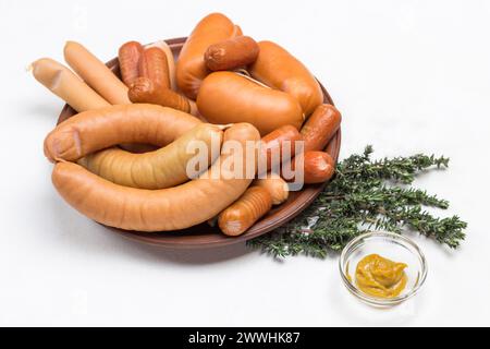 Salsicce di diverse varietà su piatto di ceramica. Senape e rafano in ciotole di vetro, rametti di timo sul tavolo. Sfondo grigio. Vista dall'alto Foto Stock