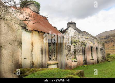 Vecchio e spaventoso albergo abbandonato con un tetto in ferro ondulato rosso parzialmente in posizione Foto Stock