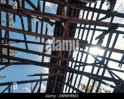 Vista dal basso del tetto di un vecchio edificio con strutture in legno contro il cielo. Tetto in legno distrutto nell'edificio abbandonato. Foto Stock