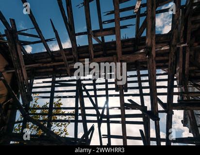 Vista dal basso del tetto di un vecchio edificio con strutture in legno contro il cielo. Tetto in legno distrutto nell'edificio abbandonato. Foto Stock