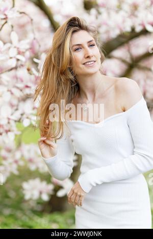 ritratto primaverile di una giovane donna ad un albero di magnolia Foto Stock