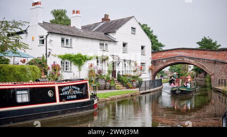 Crociera di un giorno attraverso il ponte ad arco del canale con barca ormeggiata fuori casa sul Bridgewater Canal, Inghilterra, Regno Unito, Gran Bretagna, Lymm, Cheshire Foto Stock