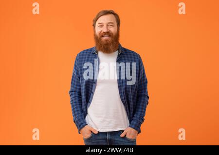 Uomo con capelli rossi e barba in posa su sfondo arancione Foto Stock