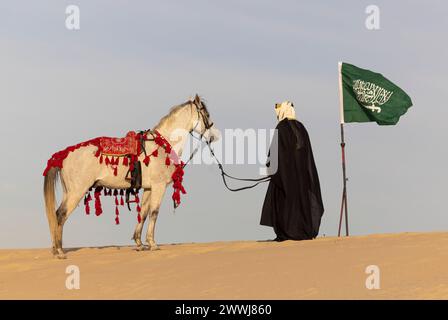 Uomo saudita in abiti tradizionali con il suo stallone bianco Foto Stock