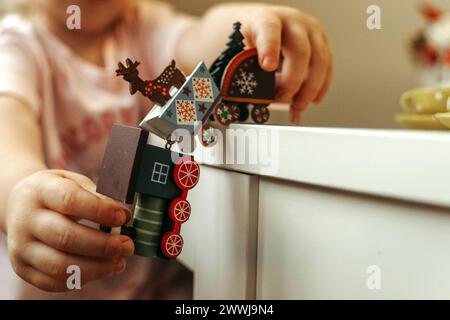 Un bambino giocherà felicemente con un colorato set di treni giocattolo, spingendo il treno lungo i binari sul pavimento. Foto Stock