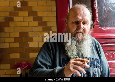 Uomo con barba che fuma sigaretta Tilburg, Paesi Bassi. Un adulto adulto adulto adulto che indossa una barba fumando una cigerette vicino alla porta d'ingresso di un ristorante caffetteria. MRYES Tilburg Spaarbank, Noordstraat Noord-Brabant Nederland Copyright: XGuidoxKoppesx Foto Stock