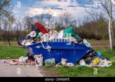 VUKICEVICA, SERBIA - 2 APRILE. 2023: Un mucchio di rifiuti alimentari, lattine, bottiglie di plastica e sacchetti di plastica viene sparso da un contenitore affollato. Foto Stock