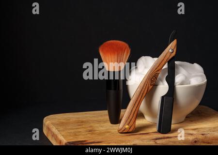 Apparecchiatura di rasatura classica con rasoio, spazzola e sapone su supporto in legno su sfondo scuro Foto Stock