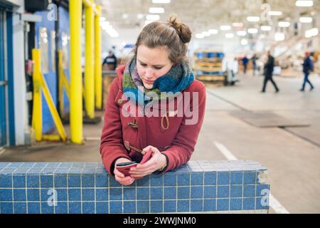 Giovane donna bruna con smartphone Bronx, New York City, USA. Yiung adulta, giornalista donna che controlla i suoi messaggi al mercato del pesce di Hunts Point. MRYES New York City New Fulton Fish Market, The Bron New York Stati Uniti d'America Copyright: XGuidoxKoppesx Foto Stock