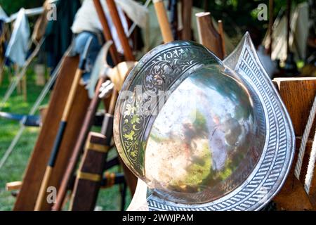 Casco militare in metallo in stile spagnolo indossato con armi medievali sullo sfondo Foto Stock