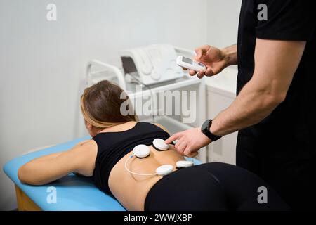 Il fisioterapista utilizza uno stimolatore elettrico muscolare Foto Stock