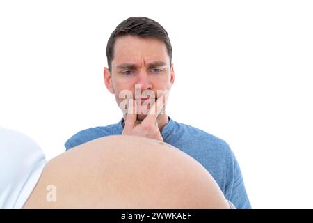 Descrizione: Il padre incinta tiene premuta la mano al mento e contempla l'urto del bambino incinta. Ultimo mese di gravidanza - settimana 39. Sfondo bianco Foto Stock