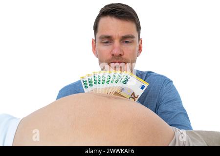 Descrizione: Il padre incinta con banconote in mano guarda con attenzione al bambino incinta di sua moglie. Ultimo mese di gravidanza - settimana 39. Wow Foto Stock