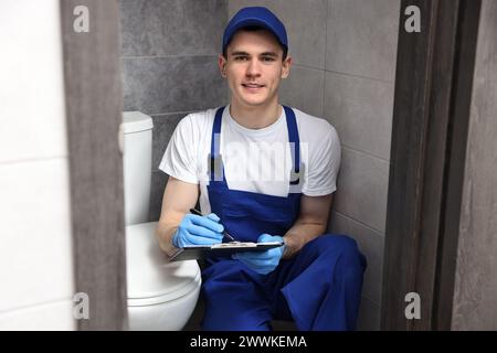 Sorridente scrittura idraulico risultati dell'esame della ciotola del water nell'armadio ad acqua Foto Stock