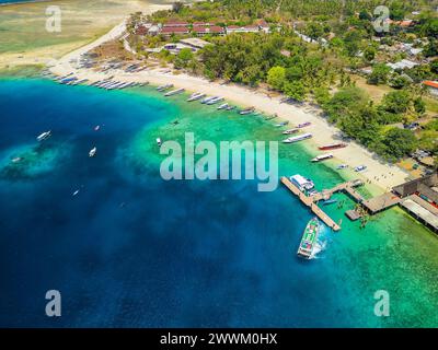 Barche che circondano una barriera corallina e una piccola isola tropicale Foto Stock