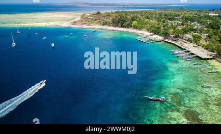 Barche che circondano una barriera corallina e una piccola isola tropicale Foto Stock