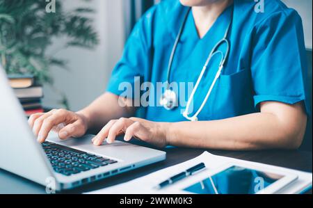 Medico donna che utilizza il suo computer portatile per la gestione dei dipendenti, il flusso di lavoro ospedaliero e la soluzione per il personale clinico su software o app. in ufficio. Foto Stock