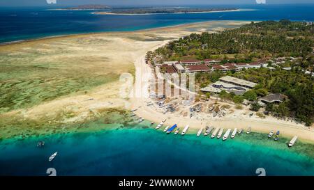 Barche su una spiaggia e barriera corallina al largo di una piccola isola tropicale in Indonesia (Gili Air) Foto Stock