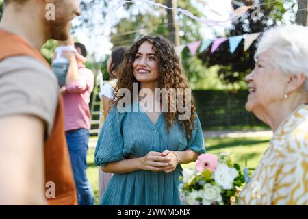 I nonni donano fiori e regalano alla nipote come sorpresa alla festa di compleanno. Amici e familiari si riuniscono alla festa in giardino dopo molto tempo Foto Stock