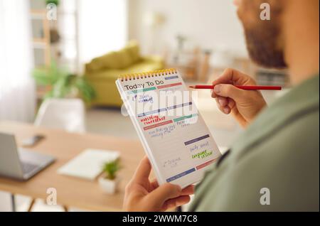 Foto ravvicinata di un uomo d'affari che scrive per fare un elenco nel suo blocco note che pianifica le attività quotidiane. Foto Stock