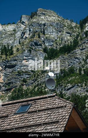 Tetto della casa di montagna con antenna satellitare sotto le montagne rocciose delle Alpi Giulie in estate, attenzione selettiva Foto Stock