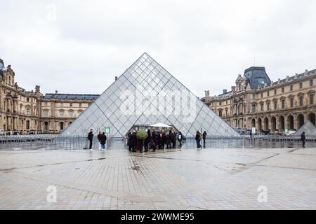 5 dicembre 2023 - turisti fuori dalla piramide di vetro all'ingresso del Museo del Louvre a Parigi, Francia Foto Stock