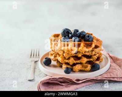 Waffle da avena facili e sani senza glutine con spazio per la copia. Pile di appetitosi waffle fatti in casa con farina d'avena mirtilli decorati, sul piatto su fondo grigio chiaro cemento Foto Stock