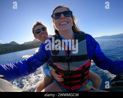 Un paio di sorrisi mentre cavalcano una WaveRunner sul lago Tahoe, California Foto Stock