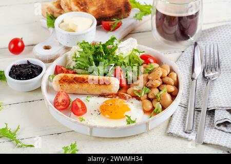 Colazione all'inglese. Colazione Keto. Uova fritte, fagioli, salsiccia di pollo e tazza di caffè. Foto Stock