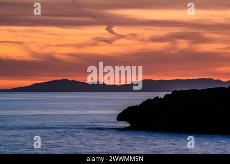 Montagne orientali dell'isola di Maiorca viste da Capo Cap d'Artrutx, a Minorca, al tramonto invernale (Minorca, Isole Baleari, Spagna) Foto Stock