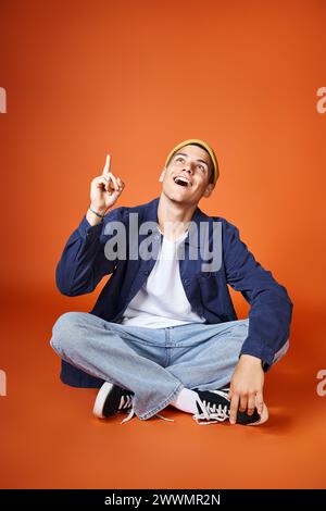 giovane allegro con cappello giallo che ha avuto un'idea sullo sfondo della terracotta Foto Stock
