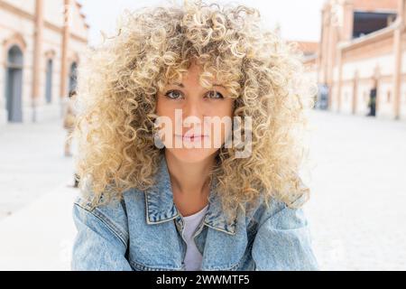 Ritratto di una giovane donna caucasica sorridente con capelli biondi ricci Foto Stock