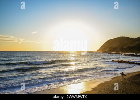 Levanto, Italia: 24 marzo 2024: Un surfista guarda al tramonto Foto Stock