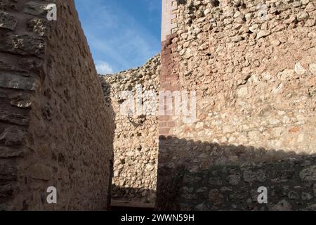 pareti di pietra sotto un cielo limpido, creando uno stretto sentiero, che mostra la struttura e la storia in un ambiente sereno. Foto Stock