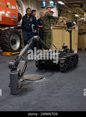 OCEANO PACIFICO (17 febbraio 2024) i marinai assegnati alla portaerei d’assalto anfibio schierata in avanti USS America (LHA 6), osservano una piattaforma robotica durante una dimostrazione di smaltimento esplosivo di Ordnance Disposal (EOD) nell’area di stoccaggio dei veicoli della nave, mentre conducono operazioni di routine nell’Oceano Pacifico, il 17 febbraio. L'America, nave di comando dell'America Amphibious Ready Group, è operativa nell'area operativa della 7th Fleet. La U.S. 7th Fleet è la più grande flotta numerata della Marina degli Stati Uniti, e interagisce e opera regolarmente con alleati e partner nel preservare un Indo-PAC libero e aperto Foto Stock