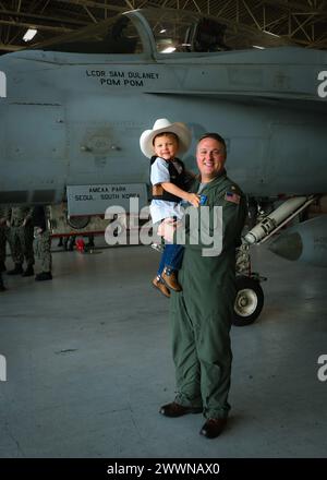 VIRGINIA BEACH, Virginia (23 febbraio 2024)- LT. Cmdr. Sam Dulaney, pilota di F/A-18E Super Hornet assegnato allo Strike Fighter Squadron (VFA) 37 “Ragin’ Bulls”, posa per una foto con suo figlio, Charlie, nella baia di aggancio dello squadrone a bordo della Naval Air Station Oceana. Charlie ha ispirato i Ragin’ Bulls, che hanno dato il nome ai loro aerei ai tori Professional Bull Riders (PBR). I Ragin' Bulls tornarono il 16 gennaio da uno schieramento di otto mesi a sostegno di partner e alleati nella 6th Fleet della Marina degli Stati Uniti d'America nell'area delle operazioni a bordo della USS Gerald R. Ford (CVN 78). Marina Foto Stock
