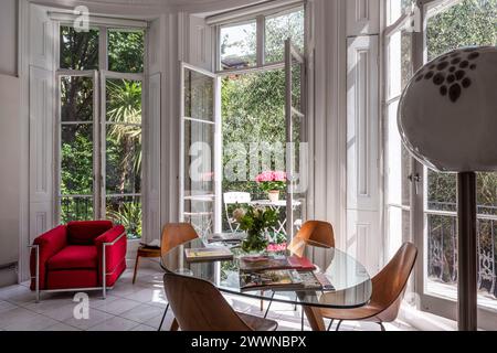 Poltrona vintage con tavolo e sedie a porte aperte nel moderno appartamento di West London, Regno Unito Foto Stock